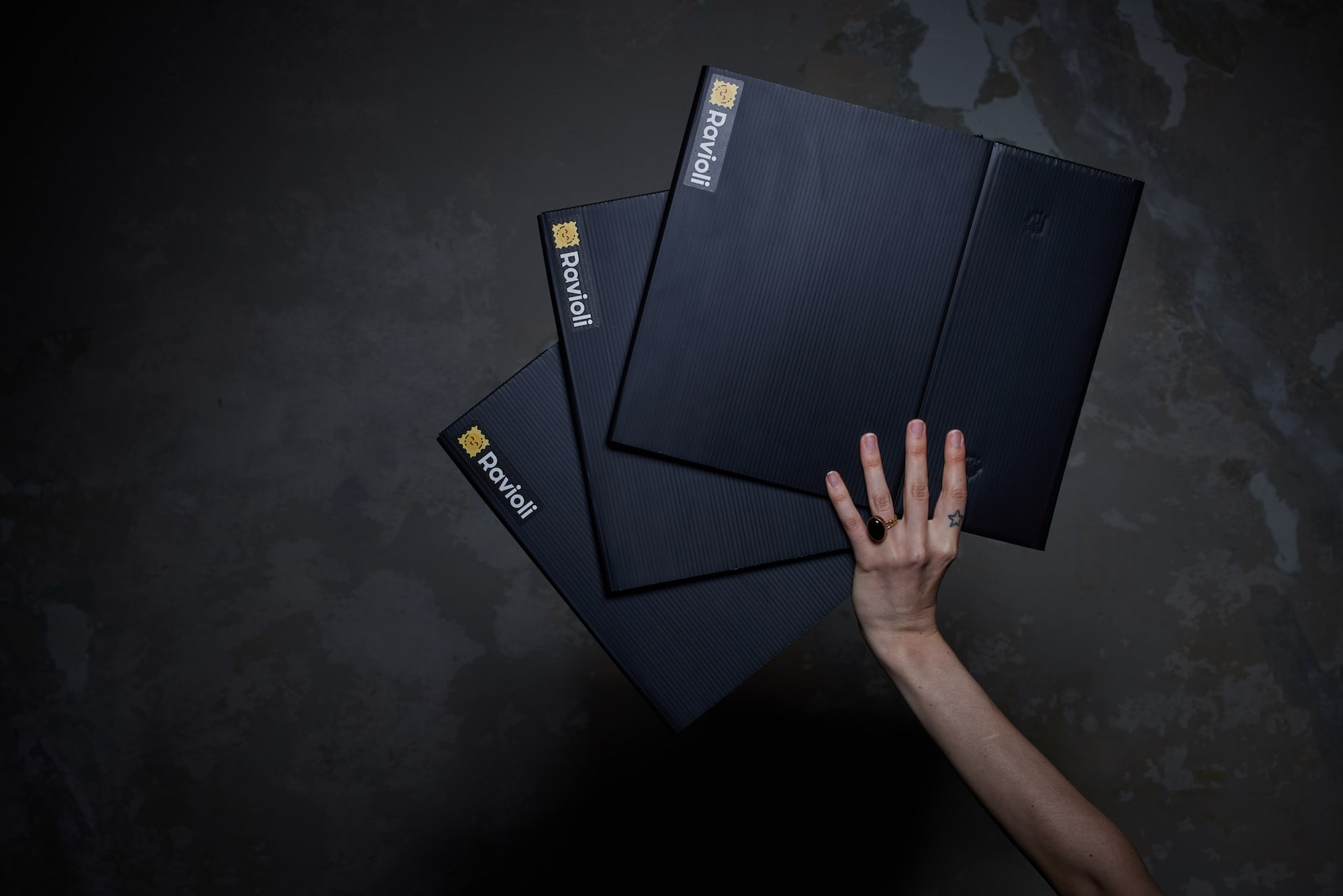 Eine Hand hält 3 gefaltete Mehrweg-Versandverpackungen von Ravioli